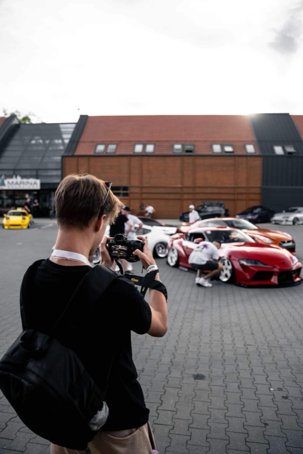 Fotograf robiący zdjęcie czerwonej Toyocie Supra na parkingu